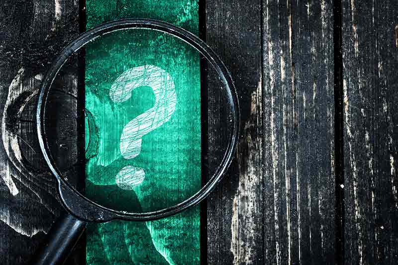 Question mark painted and magnifying glass on wooden table